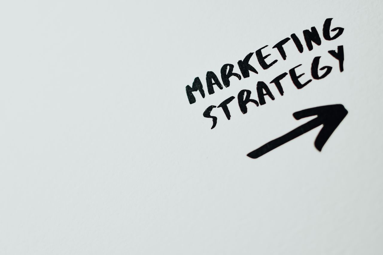 services-04 Gros plan sur le texte manuscrit Marketing Strategy avec une flèche sur fond blanc.